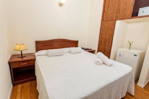 a bedroom with a large white bed and a night stand at Hotel Bahamas in Montevideo