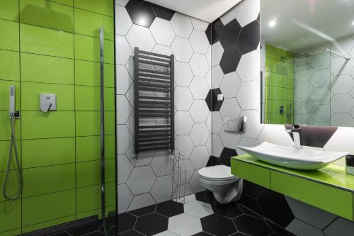 a bathroom with a sink and a toilet and a mirror at Aparthotel Delta Royal in Kościelisko