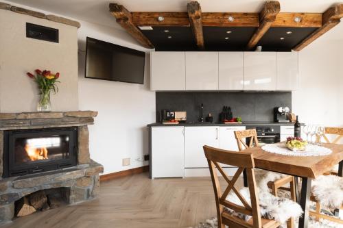 a kitchen with a fireplace and a table with chairs at Aparthotel Delta Royal in Kościelisko
