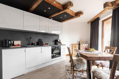 a kitchen with white cabinets and a wooden table at Aparthotel Delta Royal in Kościelisko