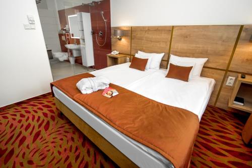 1 dormitorio con 1 cama grande y toallas. en Rubin Wellness & Conference Hotel en Budapest