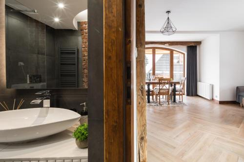 a bathroom with a white tub and a dining room at Aparthotel Delta Royal in Kościelisko