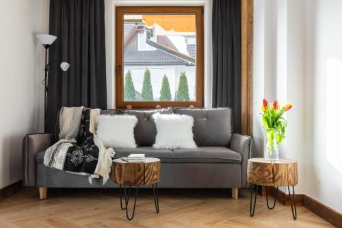 a living room with a gray couch and two tables at Aparthotel Delta Royal in Kościelisko