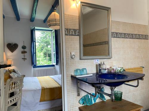a bathroom with a sink and a bed and a mirror at Vingt Vieux Bourg in Rochefort-en-Terre