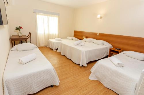 a room with four beds with white sheets at Hotel Bahamas in Montevideo
