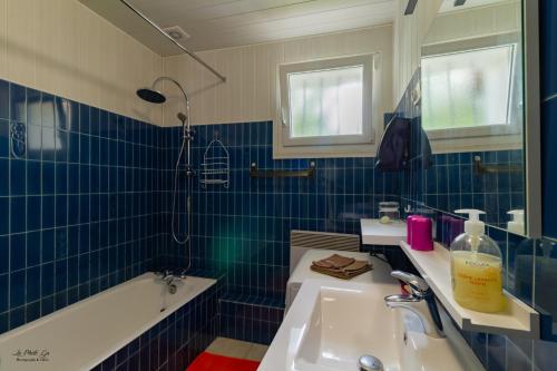 a blue tiled bathroom with a sink and a tub at Gite Des Croix Bancaud in Jumilhac-le-Grand