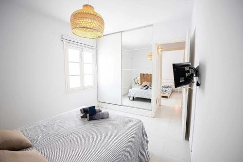 ein weißes Zimmer mit einem Bett und einem Spiegel in der Unterkunft Le Family Palms My Home in Playa Honda