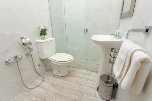 a white bathroom with a toilet and a sink at Hotel Bahamas in Montevideo