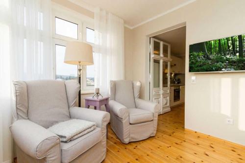 uma sala de estar com duas cadeiras e uma televisão em Villa Albertine App 08 em Ahlbeck