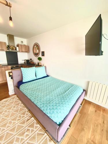 a bedroom with a large bed with a flat screen tv at - L'IROIZH - CONCARNEAU - VUE MER PANORAMIQUE - STUDIO STANDING PLAGE DES SABLES BLANCS - PARKING - DRAPS & SERVIETTES INCLUS - NEAR THALASSOTHERAPY - Wifi - in Concarneau