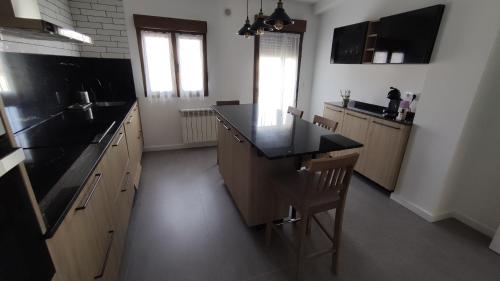 a large kitchen with a black counter top and wooden cabinets at Casa Valparaíso in San Martín de Laspra