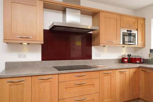 a kitchen with wooden cabinets and a stove top oven at Rent My Spa Home with Pool table Hottub and Sauna in Chesterfield