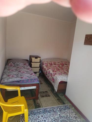 a room with two beds and a yellow chair at Guest House Regina in Bulan Sogottuu