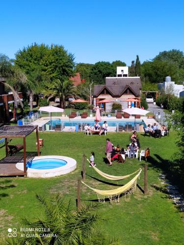 a group of people sitting in a park next to a pool at Mediterráneo Cabañas in Chascomús