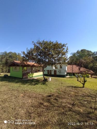 dom z drzewem pośrodku pola w obiekcie Pousada, Camping e Restaurante Recanto do Surubim w mieście São Roque de Minas