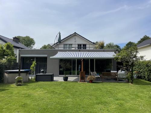 a house with awning and a yard with grass at Great house 5' from Tomorrowland in Rumst