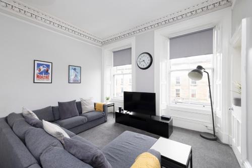 a living room with a couch and a clock on the wall at JOIVY Splendid 4-bed Flat Near The Castle in Edinburgh