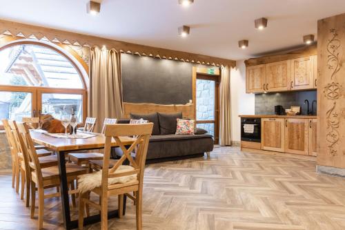 a kitchen and living room with a table and chairs at Aparthotel Delta Royal in Kościelisko