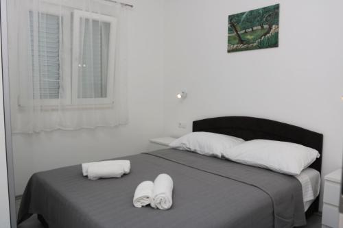 a bedroom with a bed with two towels on it at Apartmani Eni in Seget Vranjica
