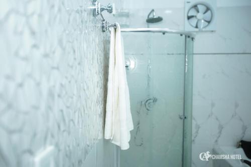 a bathroom with a shower with a white towel at Chamsha Hotel in Anuradhapura