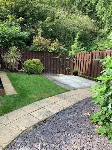 a backyard with a wooden fence and a sidewalk at Potters Brook in Framlingham