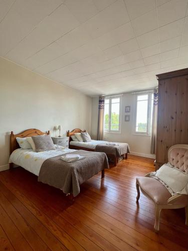 - une grande chambre avec 2 lits et une chaise dans l'établissement Honfleur house, à Honfleur