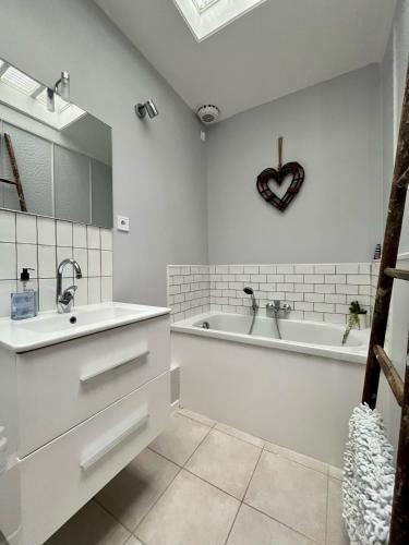 La salle de bains est pourvue d'un lavabo, d'une baignoire et d'une horloge cardiaque. dans l'établissement Honfleur house, à Honfleur