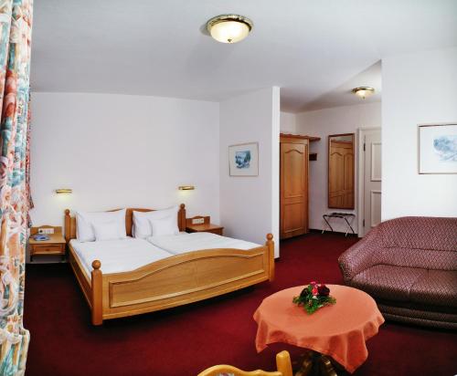 a bedroom with a bed and a couch and a table at Schloss-Gasthof Sonne in Isny im Allgäu