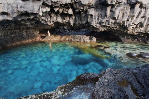 a person standing in a pool of water in a cave at MIRADOR DE MERESE in Frontera