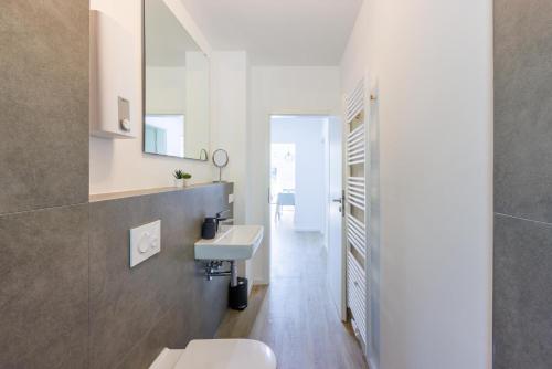 ein weißes Badezimmer mit einem Waschbecken und einem Spiegel in der Unterkunft Glück Auf Appartements Schleiermacherstraße Duisburg in Duisburg