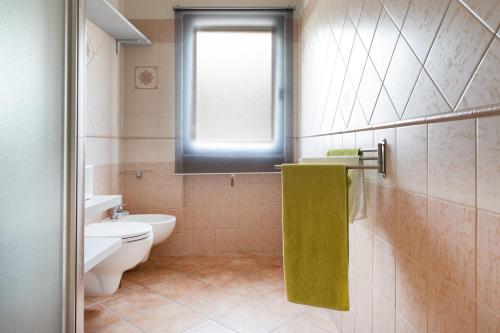a bathroom with a toilet and a window and a green towel at Appartamento La Terrazza in Portoferraio