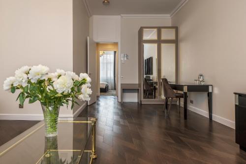 a living room with a vase of flowers on a glass table at St Palace Hotel in Vilnius