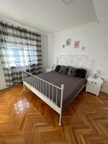 a bedroom with a white bed and a wooden floor at Apartment Cactus 021 in Novi Sad