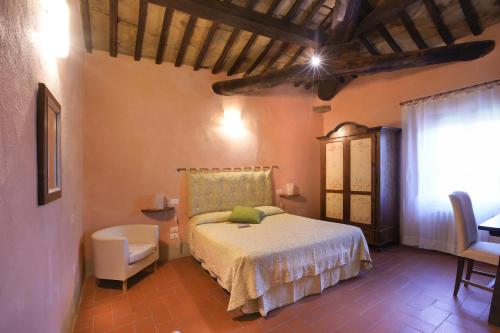 a bedroom with a bed and a chair and a window at Locanda Del Viandante B&B in Anghiari
