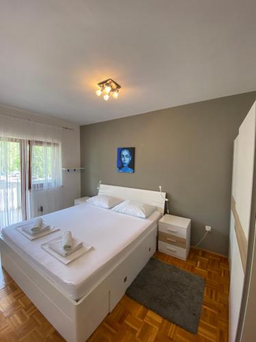 una camera da letto con un letto bianco e un dipinto blu sul muro di Apartments Irina a Rovanjska