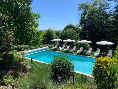 une piscine avec chaises longues et parasols dans l'établissement la gazouillerie - pleine nature, à Lauresses