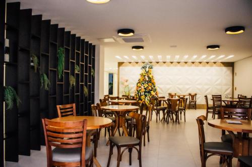 um restaurante com mesas e cadeiras e uma árvore de Natal em Resort Ecoar em Gaspar