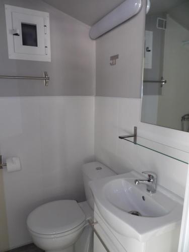 a white bathroom with a toilet and a sink at Oasis Country Park in Rugat