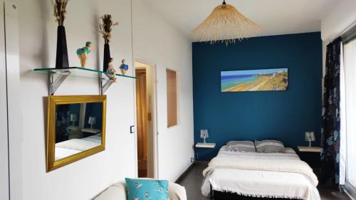 1 dormitorio con pared azul, cama y espejo en Belle Suite Apt, en Biarritz