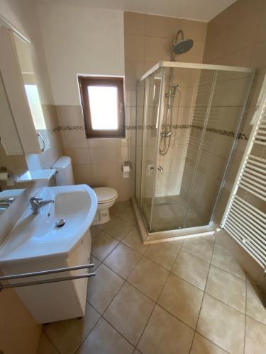 a bathroom with a shower and a sink and a toilet at Apartmani Kuprešak in Banja Vrućica