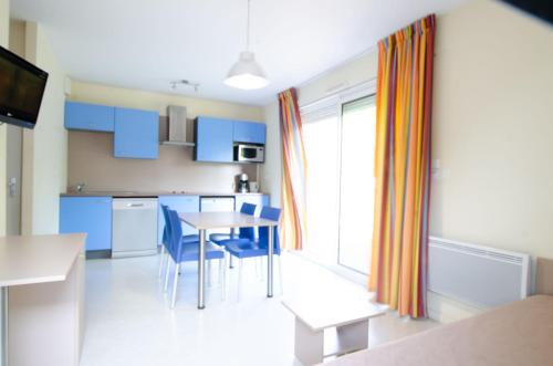 eine Küche mit blauen Schränken sowie einem Tisch und Stühlen in der Unterkunft Appartement 4 personne sur Parc Vacances Richelieu in Chaveignes