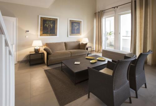 a living room with a couch and a table and chairs at Cannes Croisette Prestige Apart'hotel in Cannes