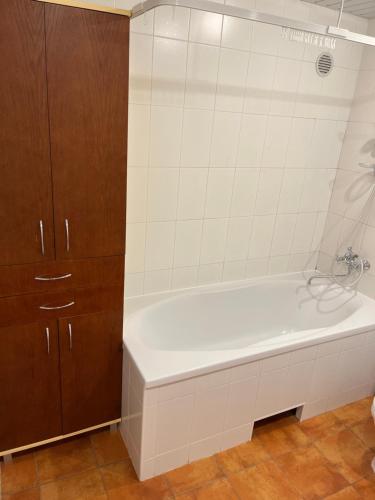 a white bath tub in a bathroom with brown cabinets at Domo Vila in Klaipėda