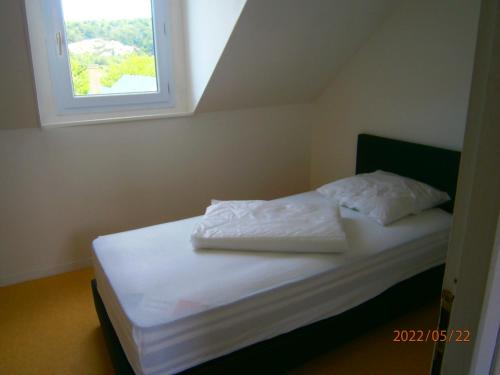 ein Bett mit weißer Bettwäsche und ein Fenster in einem Zimmer in der Unterkunft Agréable petite maison in Fécamp
