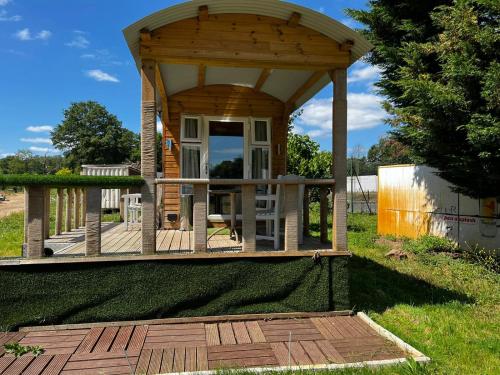 un kiosque en bois sur une terrasse dans un champ dans l'établissement The Caduceus Quality Budget Cabins, à Chertsey
