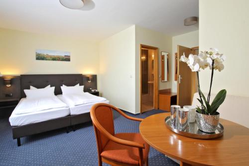 ein Hotelzimmer mit einem Bett und einem Tisch in der Unterkunft Hotel Am See in Baabe