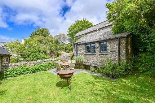 a stone house with a table and a chair in the yard at Heale Farm Cottage in Trentishoe