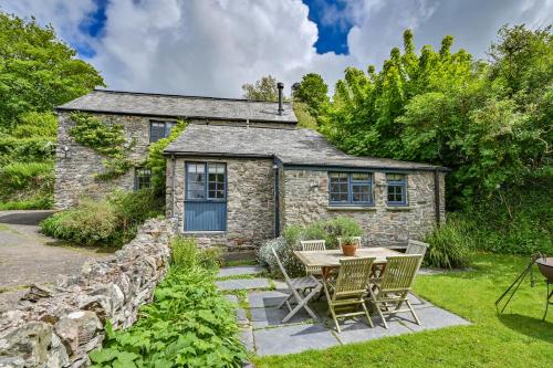 een stenen huisje met een tafel en stoelen ervoor bij Heale Farm Cottage in Trentishoe