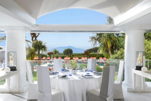 a white dining room with a white table and chairs at Jumeirah Capri Palace in Anacapri