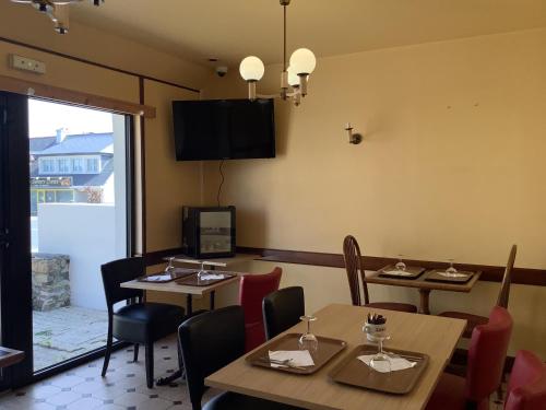 a dining room with tables and chairs and a television at Le village Gr34 louannec in Louannec